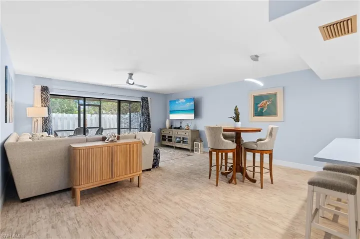 Living room with visible vents, ceiling fan, light wood-type flooring, and baseboards