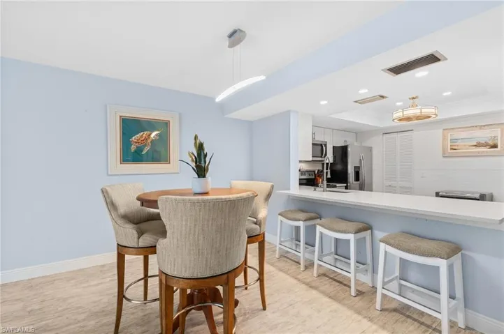 Dining area with baseboards, visible vents, light wood finished floors, recessed lighting, and a raised ceiling