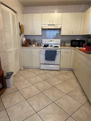Kitchen featuring ventilation hood, stove, tasteful backsplash, and light tile floors