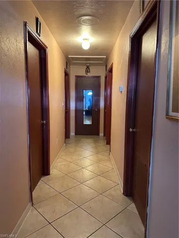 Hall with light tile floors and a textured ceiling