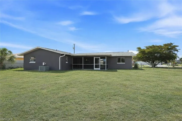 Rear view of property featuring a yard, stucco siding, and a sunroom