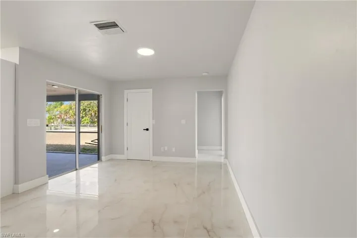Unfurnished room featuring light marble finish flooring and baseboards