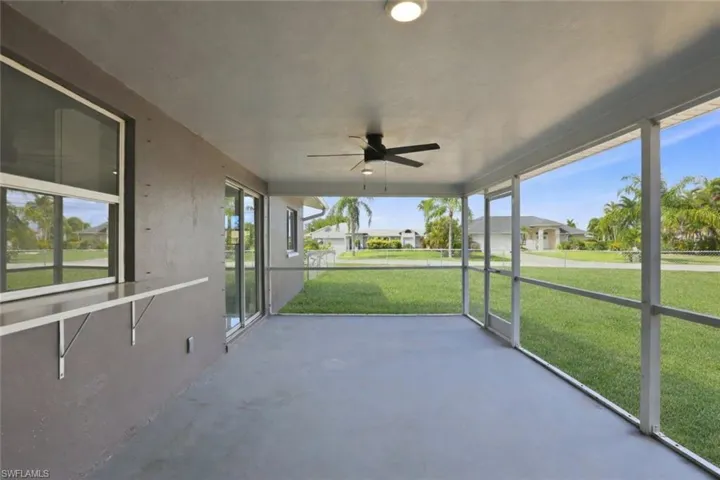 Unfurnished sunroom with a ceiling fan and a residential view