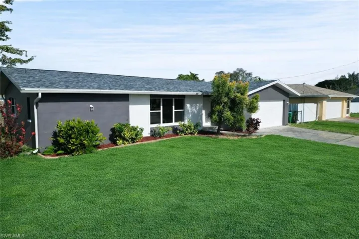 Ranch-style home with a front yard, stucco siding, a shingled roof, driveway, and an attached garage