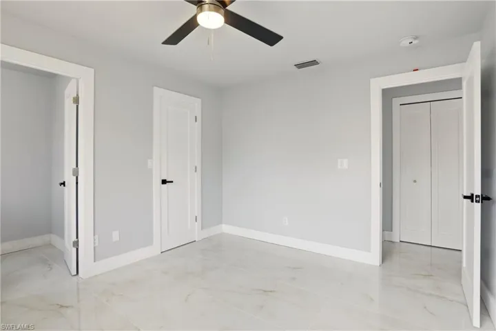 Unfurnished bedroom featuring a ceiling fan and light marble finish flooring