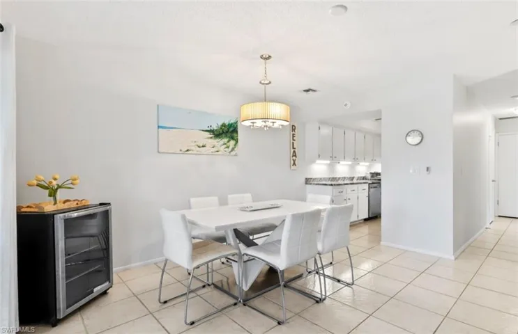 Open-concept dining area featuring tile flooring, a contemporary chandelier, and a pass-through opening to the kitchen