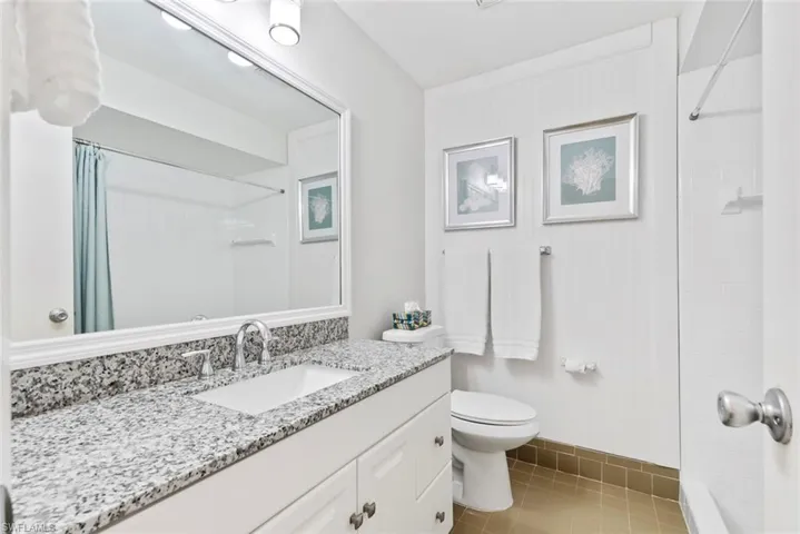 Bathroom with a granite-style countertop, integrated sink, and white vanity cabinetry