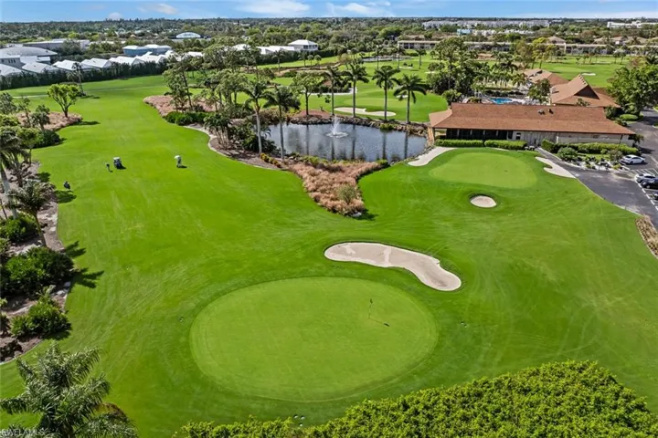 Expansive golf course featuring a green, sand traps, and a water hazard with a fountain