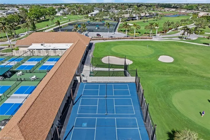 Expansive property featuring multiple blue-surfaced pickleball courts, a large blue-surfaced tennis court, and a meticulously maintained golf course with sand traps