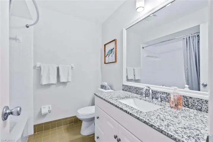 Bathroom featuring a white vanity with a granite countertop, undermount sink, and chrome faucet