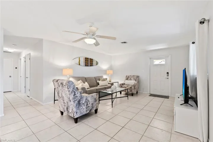 Spacious living area featuring light-toned tile flooring, recessed lighting, and a ceiling fan with integrated illumination