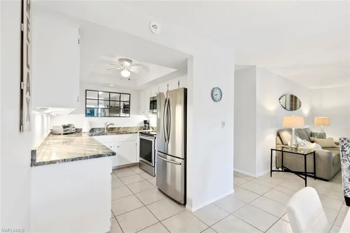Kitchen area featuring white cabinetry, stone-finish countertops, and stainless steel appliances