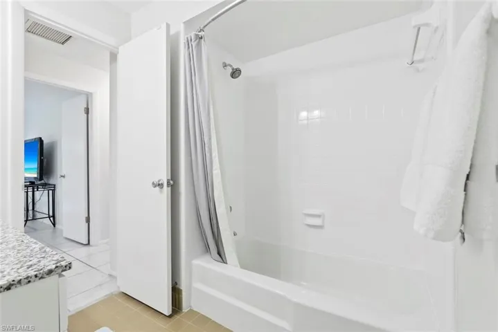 White subway tile shower surround with integrated tub, shower head, and curved shower rod