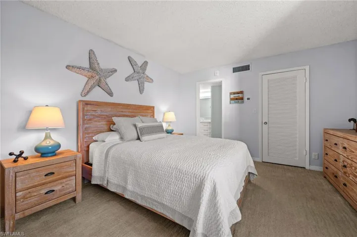 Bedroom with light colored carpet and a textured ceiling