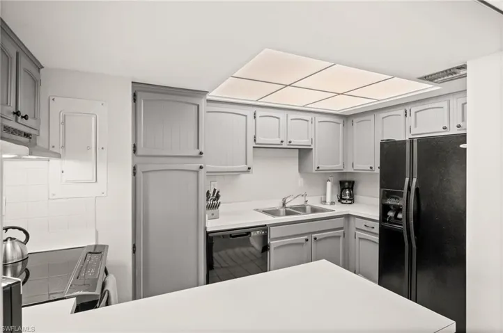 Kitchen with black appliances, backsplash, electric panel, and light countertops