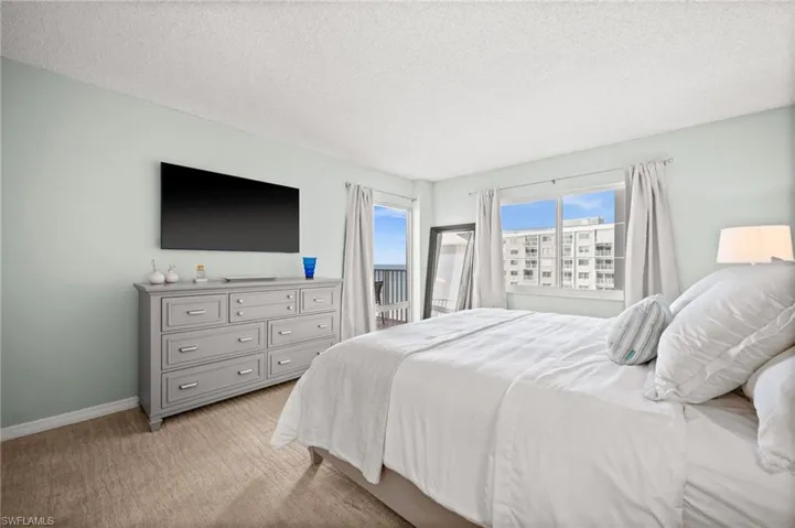 Bedroom with a textured ceiling, light carpet, and access to exterior