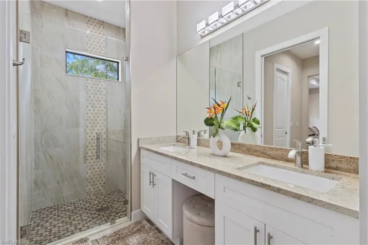 Spacious bathroom featuring a frameless glass shower enclosure with a horizontal window and mosaic tile floor