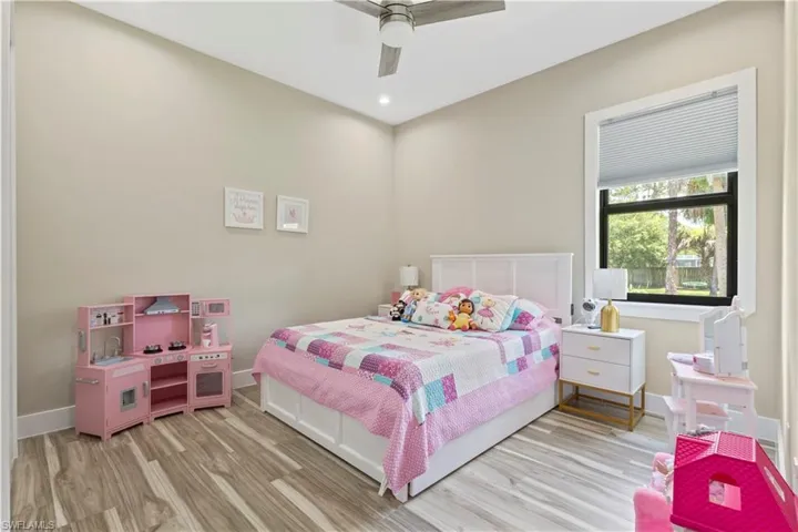 Spacious bedroom featuring wood-finish flooring, a contemporary ceiling fan, recessed lighting, and a large window with privacy blinds