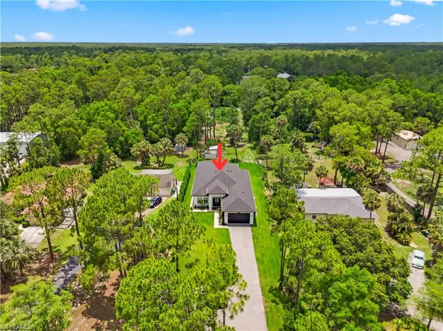 Extensive green landscaping encompasses this property, featuring a long paved driveway leading to a two-car garage