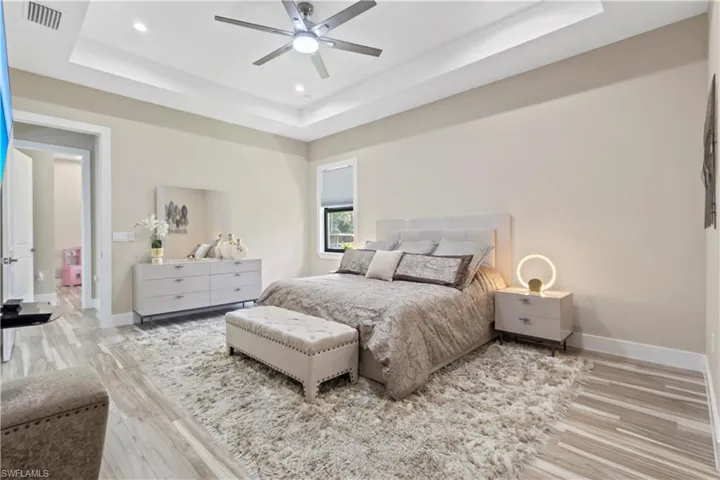 Spacious interior featuring a contemporary ceiling fan, recessed lighting, tray ceiling, and wood-finish flooring