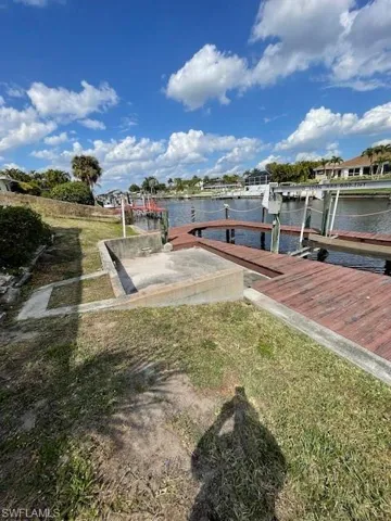 Dock with boat lift, a water view, and a yard
