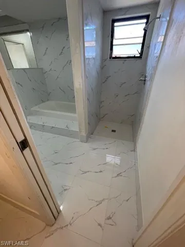 Bathroom featuring a marble finish shower, light marble finish floors, and a bath