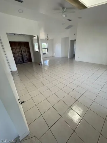Spare room featuring hanging lights, light tile patterned flooring, vaulted ceiling, and a ceiling fan