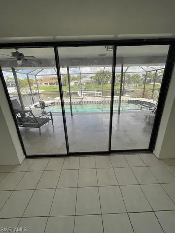 Doorway to outside featuring a sunroom, tile patterned flooring, plenty of natural light, and ceiling fan