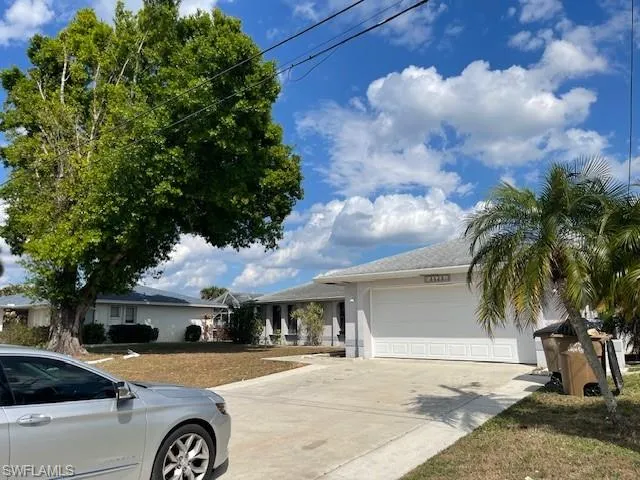 Ranch-style home with a garage, driveway, a front lawn, and stucco siding
