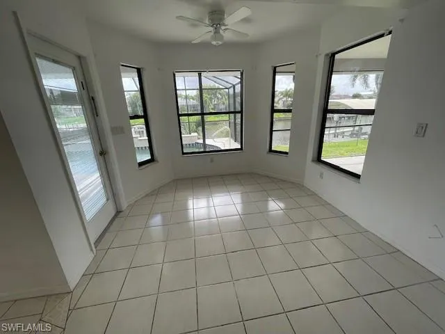 Empty room with light tile patterned floors and a chandelier