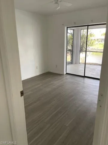 Unfurnished room featuring dark wood-style floors, a water view, and ceiling fan