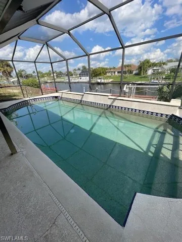 Outdoor pool with a sunroom, a lanai, a water view, a residential view, and a boat dock