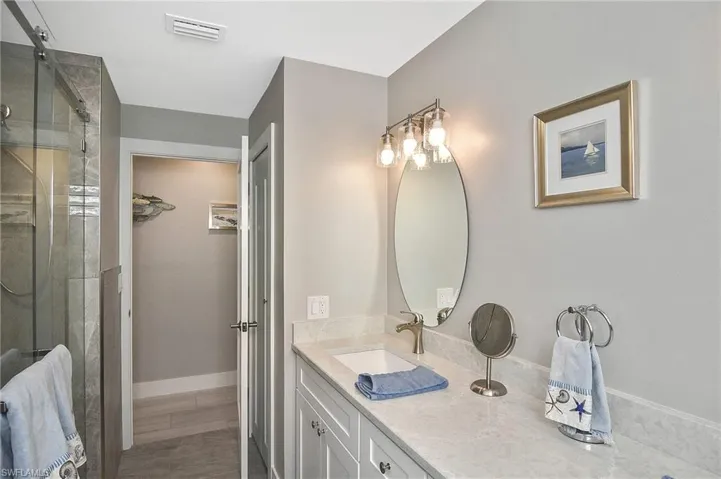 Bathroom featuring vanity, baseboards, a stall shower, visible vents, and wood finished floors