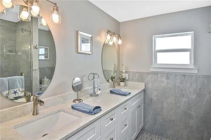 Full bathroom with tile walls, a wealth of natural light, a sink, and a stall shower