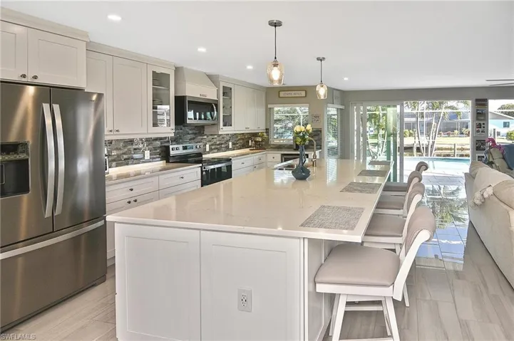 Kitchen featuring an island with sink, a breakfast bar area, light stone countertops, stainless steel appliances, and decorative backsplash