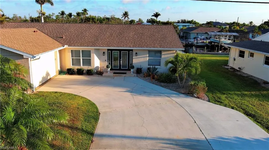 Single story home with concrete driveway, stucco siding, a front lawn, a residential view, and a shingled roof