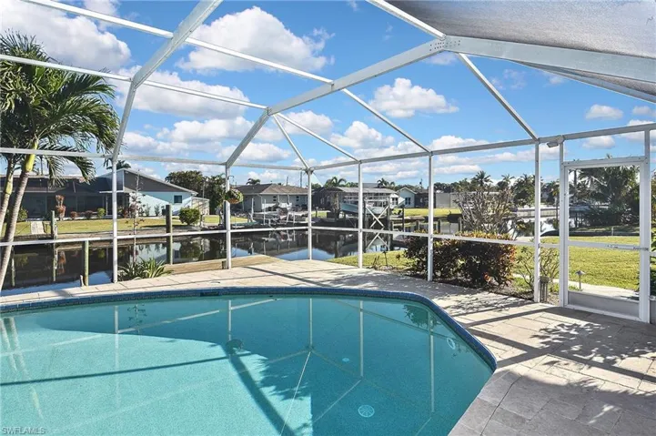 Outdoor pool featuring glass enclosure, a water view, a residential view, and a patio area
