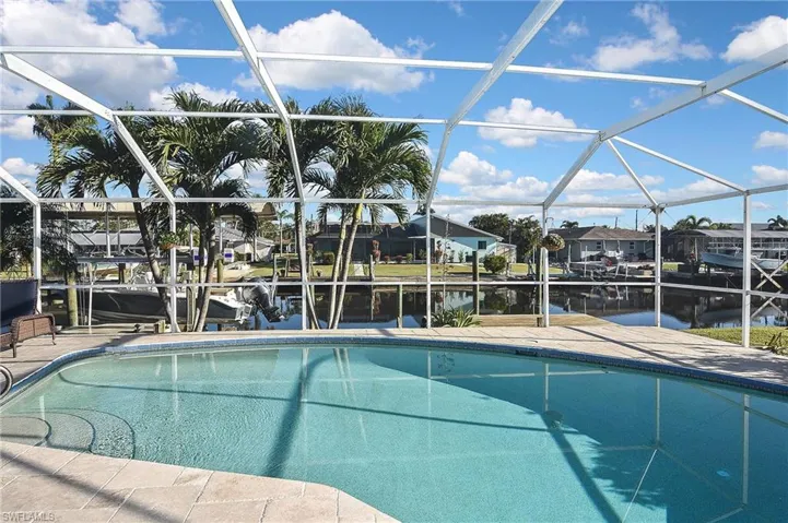 Outdoor pool with glass enclosure, a residential view, a patio area, and a boat dock