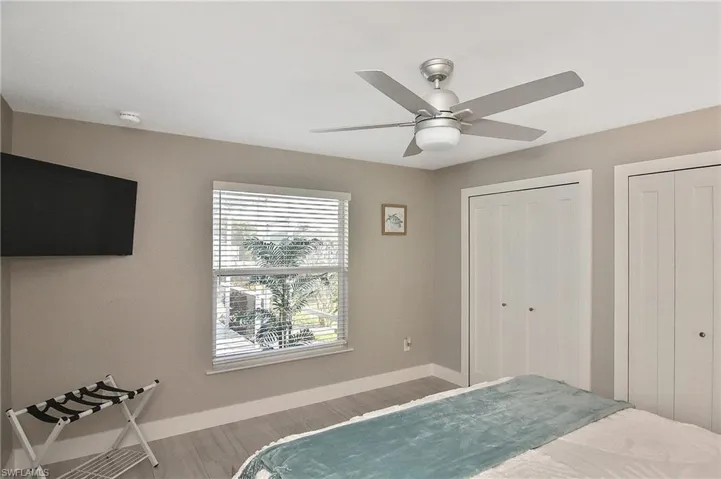 Bedroom with baseboards, ceiling fan, wood finished floors, and two closets