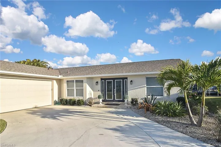 Ranch-style house with driveway, stucco siding, a garage, and french doors