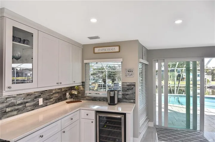 Kitchen featuring light countertops, white cabinets, glass insert cabinets, and beverage cooler
