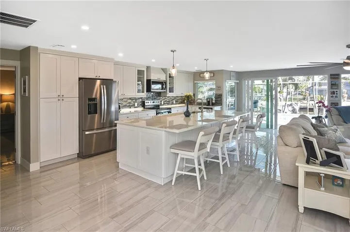 Kitchen featuring visible vents, a kitchen bar, stainless steel appliances, a spacious island, and open floor plan
