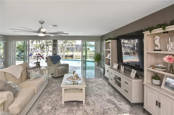 Living area with a wealth of natural light, visible vents, and ceiling fan