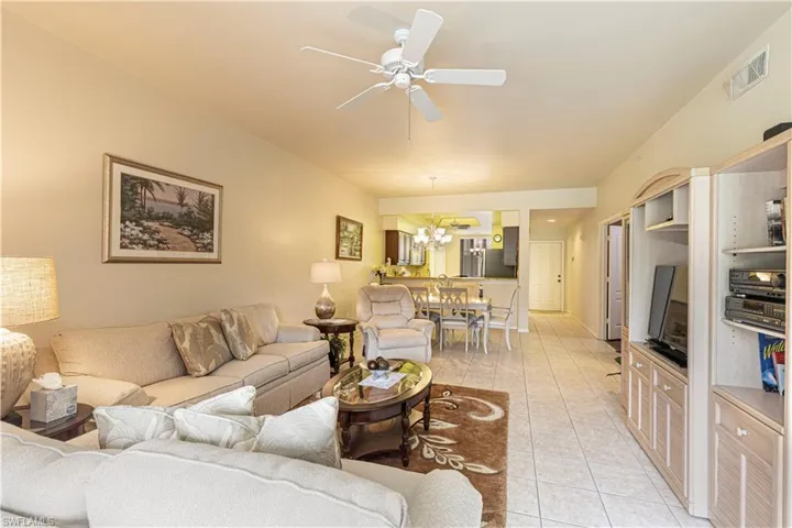 Tiled living room with ceiling fan with notable chandelier