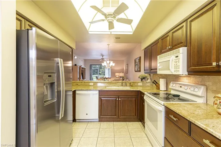 Kitchen featuring a skylight, sink, pendant lighting, light tile patterned floors, and white appliances