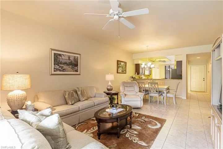 Tiled living room featuring ceiling fan with notable chandelier