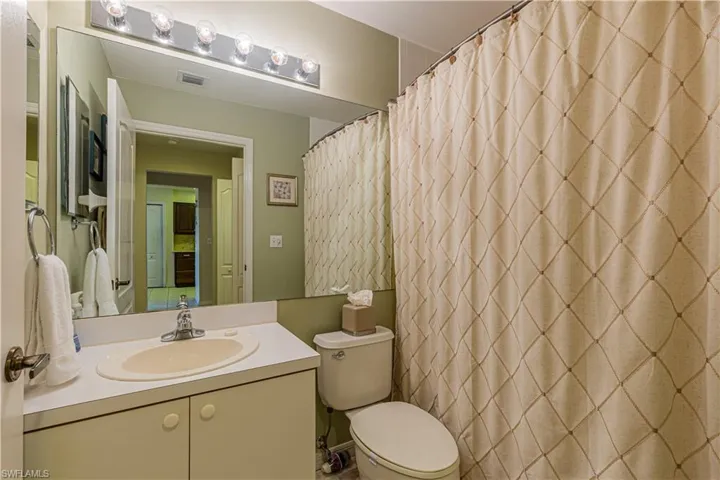 Guest bathroom with a shower with shower curtain, toilet, and vanity