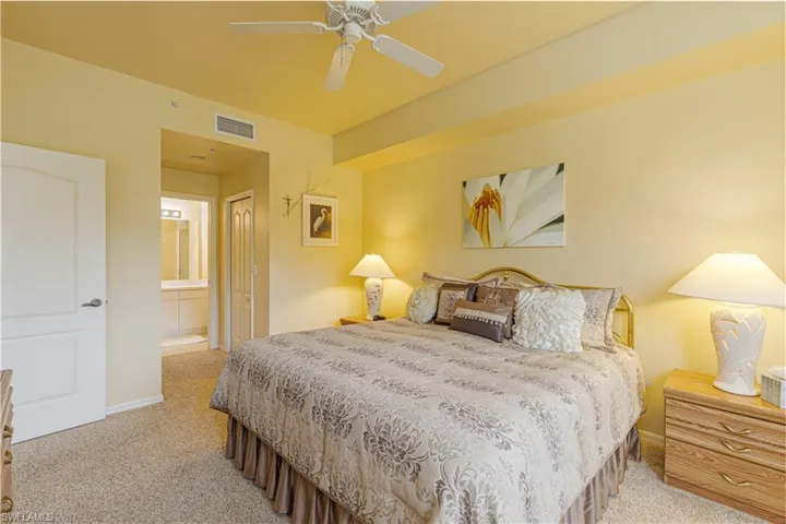 Primary carpeted bedroom with ceiling fan and ensuite bathroom