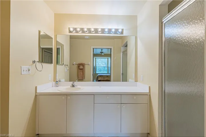 Primary bathroom with ceiling fan, vanity, and a shower with shower door