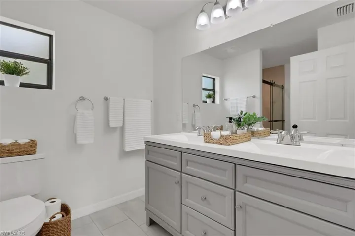 Full bath featuring double vanity, a walk -in shower and light tile patterned floors